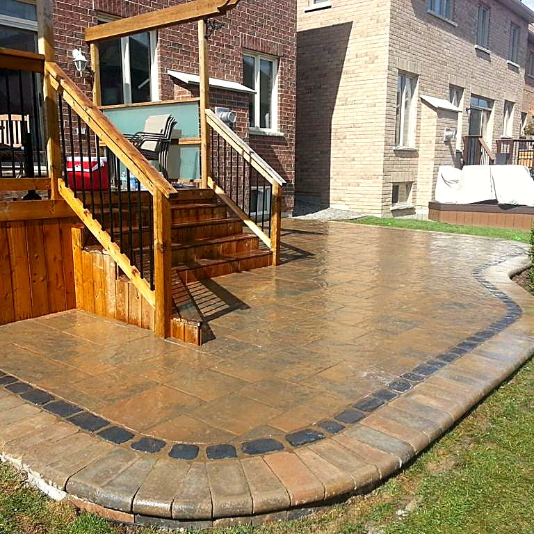 Warm-toned patio with charcoal border beside a wood deck